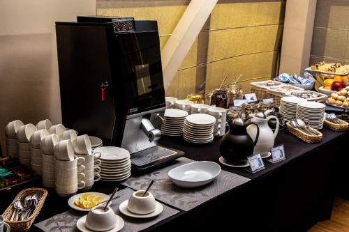 a table with plates and cups and dishes on it at Hotel Olimp Business & Spa in Wejherowo