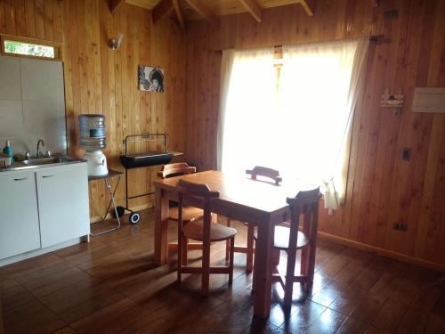 une cuisine avec une table et des chaises ainsi qu'une fenêtre dans l'établissement Bungalow Playa Linda 2, à Pucón