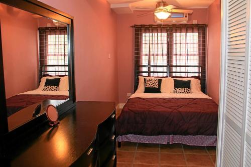 a bedroom with two beds and a desk and two windows at CosyNest in Basse Terre Town