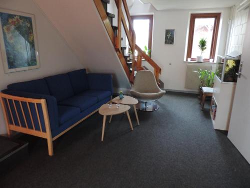 a living room with a blue couch and a staircase at Ibsens Gaard in Ebeltoft