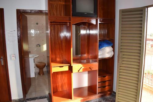 ein Holzschrank mit einem Fernseher in einem Zimmer in der Unterkunft Império Hotel in Caçu