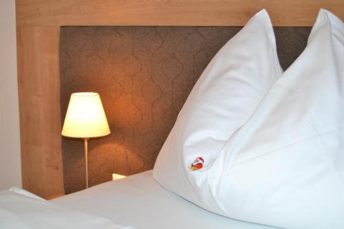 a bed with white sheets and a lamp and a pillow at Gästehaus Elisabeth in Radstadt