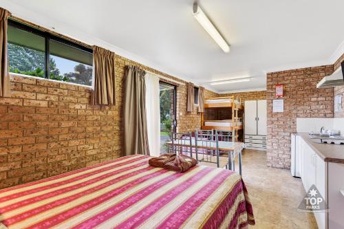 a bedroom with a bed and a brick wall at Fossicker Caravan Park in Glen Innes