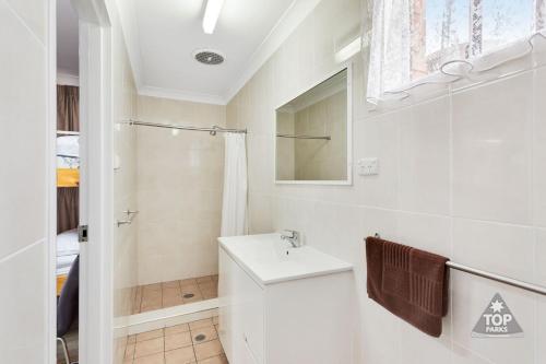 a bathroom with a toilet and a sink and a shower at Fossicker Caravan Park in Glen Innes