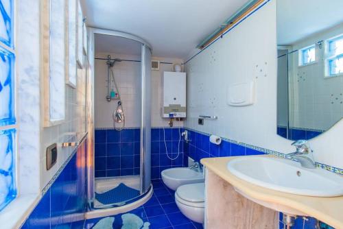 a blue and white bathroom with two toilets and a sink at La Stanzetta in Naples