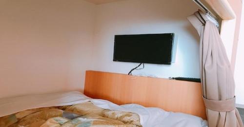 um quarto com uma cama e uma televisão de ecrã plano na parede em KIBOTCHA-Men's dormitory / Vacation STAY 8349 em Higashimatsushima