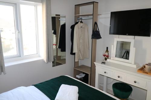 a bedroom with a bed and a dresser with a television at Riverside Rooms in Reading