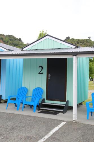a row of blue benches in front of a building at Kaiteriteri Reserve Cabins in Kaiteriteri