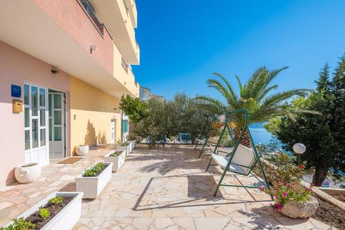 a patio with chairs and trees next to a building at Adriatic Blue Apartments in Lokva Rogoznica