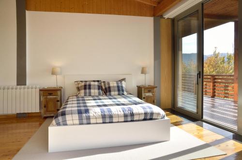 a white bedroom with a bed and a balcony at Quinta da Longra in Alvarenga