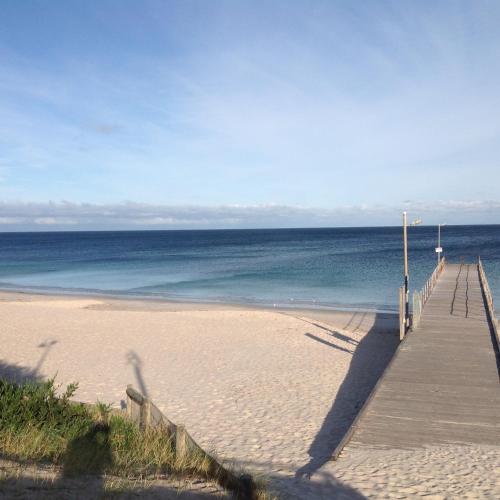 a wooden boardwalk leading to a beach with the ocean at Jetty Rd Granny Flat in Normanville