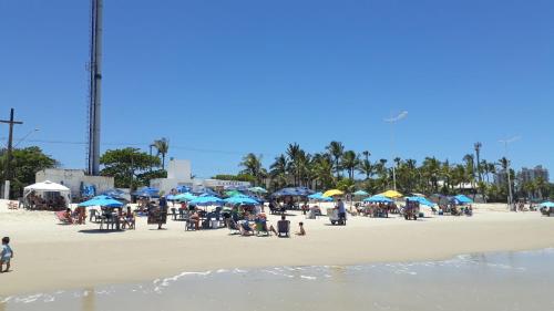 un grupo de personas sentadas en una playa con sombrillas en Condomínio Fechado - Enseada - Lazer Total, en Guarujá