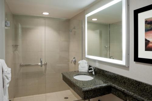 La salle de bains est pourvue d'un lavabo et d'une douche. dans l'établissement PB Surf Beachside Inn, à San Diego