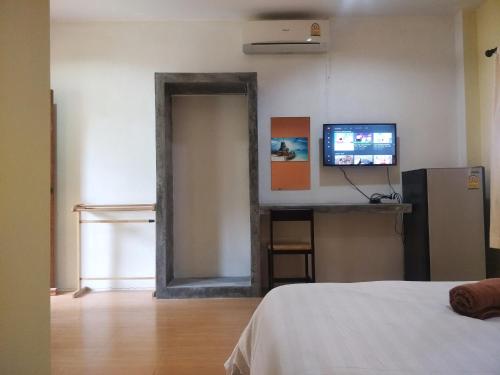 a room with a bed and a tv and a mirror at Prukrom Lanta Guesthouse in Ko Lanta