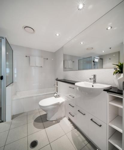 a white bathroom with a toilet and a sink at Quest River Park Central in Brisbane