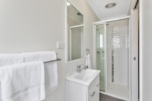 La salle de bains blanche est pourvue d'un lavabo et d'une douche. dans l'établissement Narrabri Big Sky Caravan Park, à Narrabri