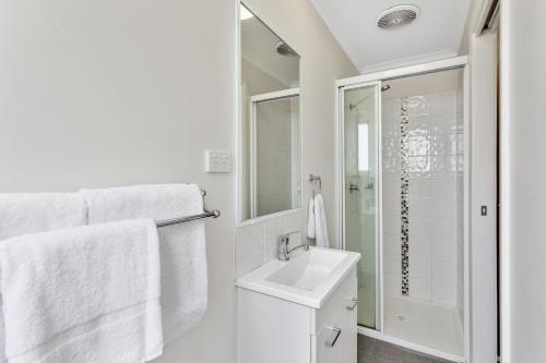 a white bathroom with a sink and a shower at Narrabri Big Sky Caravan Park in Narrabri