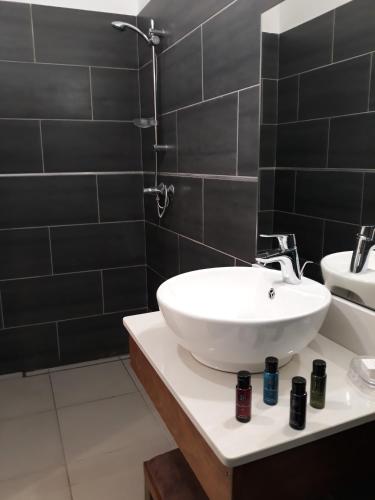 a bathroom with a white sink and black tiles at Villa Clémence in Le François