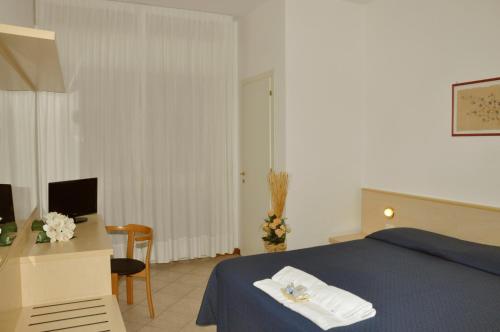 una camera con letto e scrivania con computer di Florentia Hotel a Lido di Camaiore