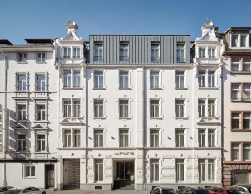 un gran edificio blanco con coches estacionados frente a él en The Pure, Frankfurt, a Member of Design Hotels en Frankfurt