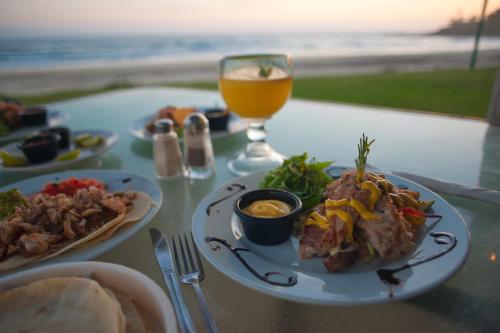 a table with a plate of food and a glass of orange juice at Cerritos Surf Town - Beach Front Property in El Pescadero