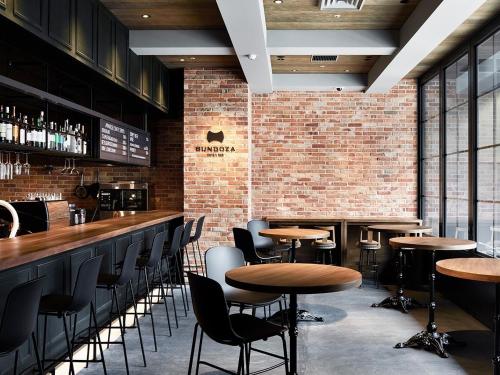 a bar with tables and chairs and a brick wall at the square hotel GINZA in Tokyo