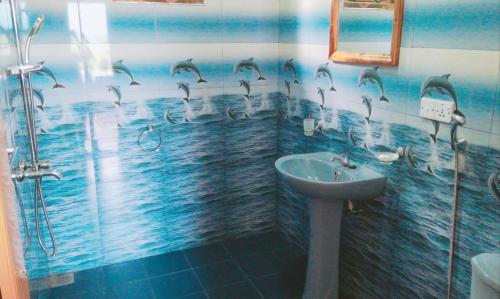 a bathroom with a shower with dolphins on the wall at Broad view in Ella