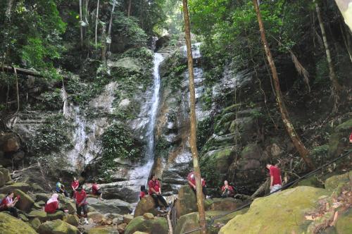 a group of people standing in front of a waterfall at Permai Rainforest Resort in Santubong