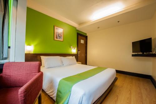 - une chambre avec un lit blanc et un mur vert dans l'établissement The Seasons Bangkok Huamark - SHA, à Bangkok