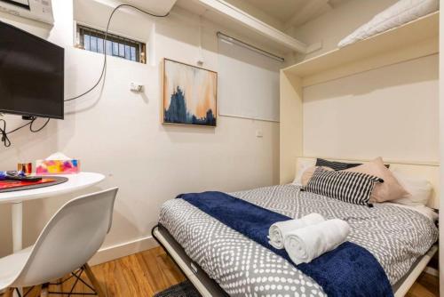 a small bedroom with a bed and a desk at Readyset Apartments on Anthony in Melbourne