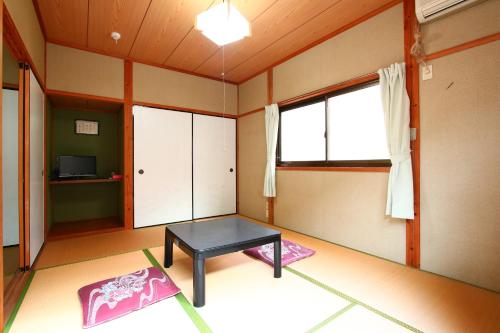 a living room with a table and a window at Ramune Onsen Senju no Sato in Kirishima