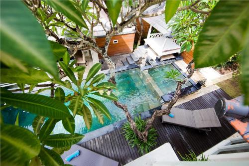 an overhead view of a swimming pool with chairs and trees at Bugan Villas in Seminyak