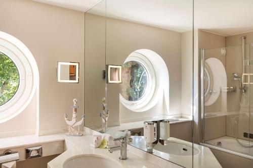 a bathroom with a sink, mirror, toilet and bathtub at Best Western Premier Alsterkrug Hotel in Hamburg