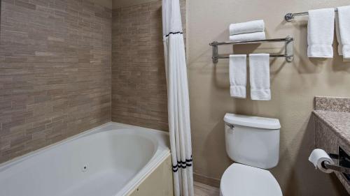 a bathroom with a tub and a toilet and a sink at Best Western Plus Lubbock Windsor Inn in Lubbock