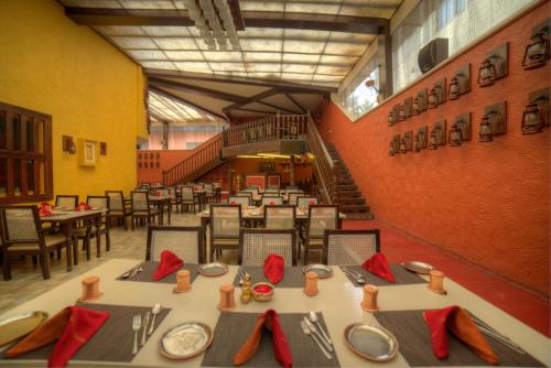 a dining room with tables and chairs and a staircase at Goldfinch Hotel Bangalore in Bengaluru