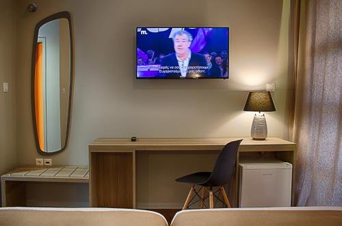 um quarto com uma televisão numa parede com uma cadeira em Athlos Hotel em Tessalônica