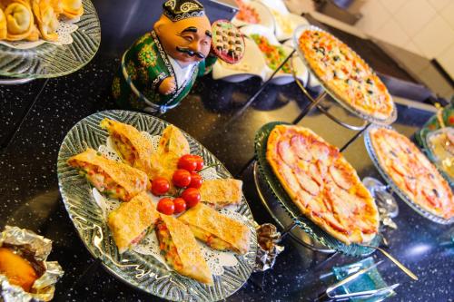 タシュケントにあるシティ パレス ホテル タシュケントのピザなどの食べ物が盛られたテーブル
