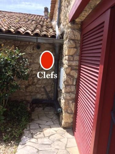 a building with a red door and a sign on it at annexe du Mesnil in Le Tourne