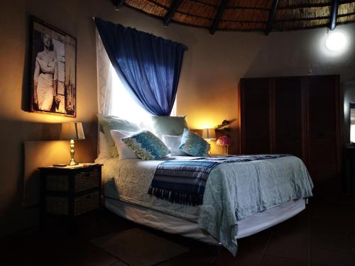 a bedroom with a bed with a blue blanket and a window at Dublin Guest House in Sabie