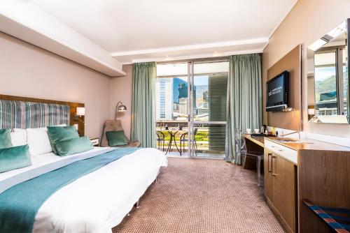 una camera d'albergo con un grande letto e una TV di aha Harbour Bridge Hotel & Suites a Città del Capo