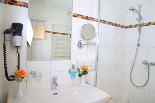 uma casa de banho com um chuveiro e um lavatório com flores em Gasthof Engelhof em Gmunden