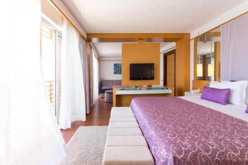 a hotel room with a bed and a tv at Kefaluka Resort Ultra All Inclusive in Akyarlar