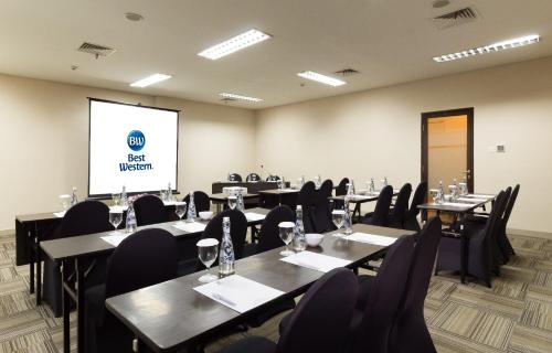 a conference room with tables and chairs and a screen at Best Western Papilio Hotel in Surabaya