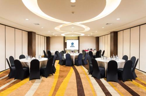 a conference room with tables and chairs and a screen at Best Western Papilio Hotel in Surabaya