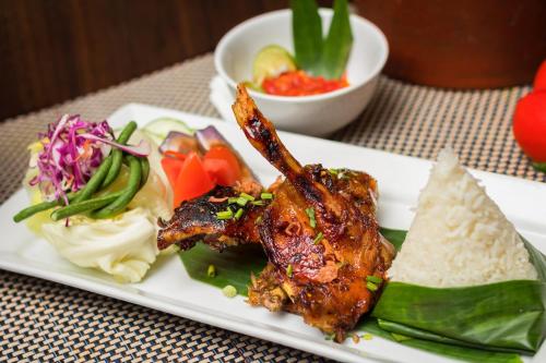 a plate of food with meat and vegetables on a table at Best Western Papilio Hotel in Surabaya
