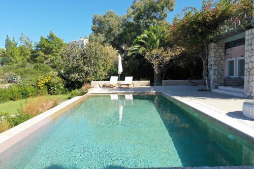 a swimming pool in a yard with two chairs in it at Villa Iris - Luxury traditional beachfront villa with swimming pool in Koilás