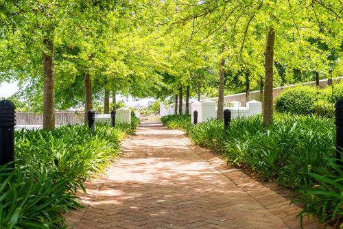 a walkway through a park with trees and grass at De Zalze Lodge in Stellenbosch