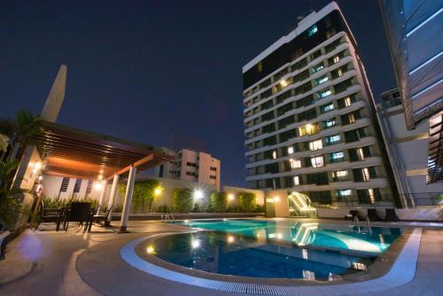 a swimming pool in front of a building at night at Gold Orchid Bangkok Hotel in Bangkok