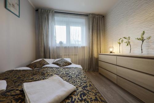 a bedroom with a bed with a dresser and a window at RentPlanet - Apartament Kościelna in Zakopane