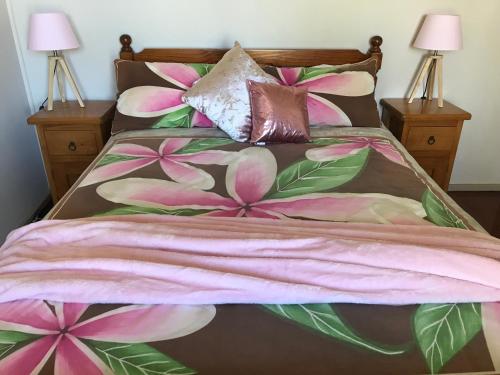 CurrarongにあるBull Ray Beach Houseのピンクの花と枕が飾られたベッド